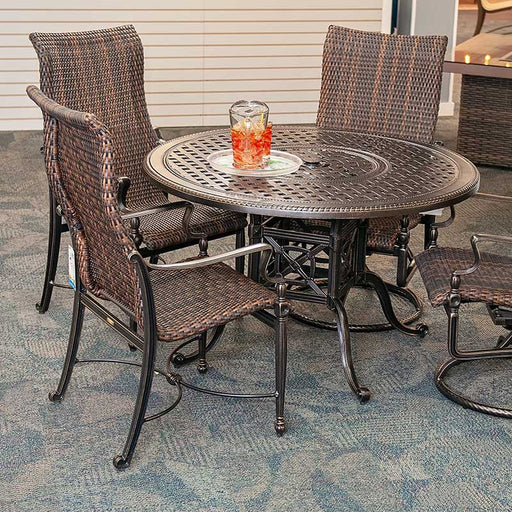 Round aluminum patio dining set surrounded by 4 woven patio dining chairs
