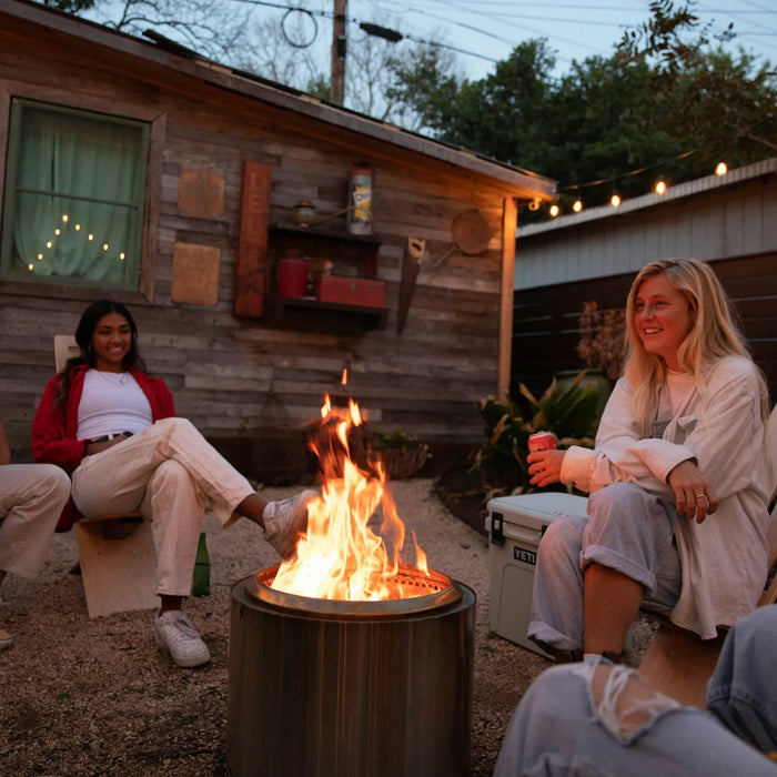 A group of friends sitting in their Outdoor Dining Set with fire pit in the Fall