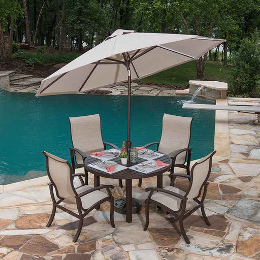 Outdoor dining set with brown finish and sling chairs sitting next to a pool