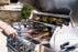 man grilling burgers and peppers on a stainless steel saber 4-burner grill